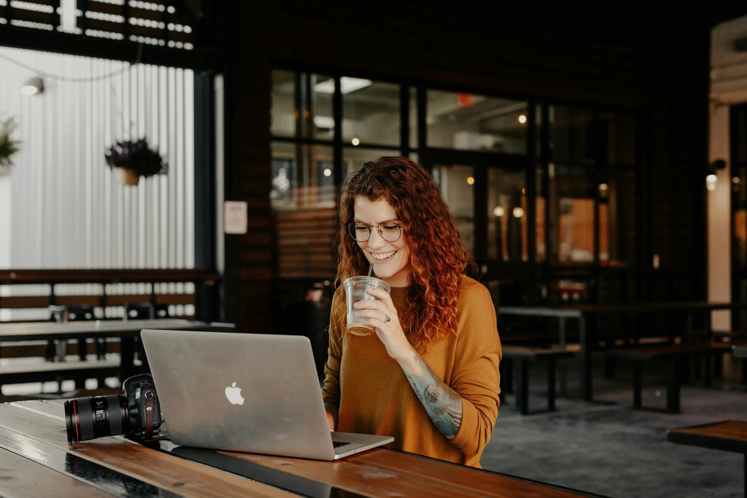 Woman writing on a laptop in a cafe, using AI to draft content in her own voice