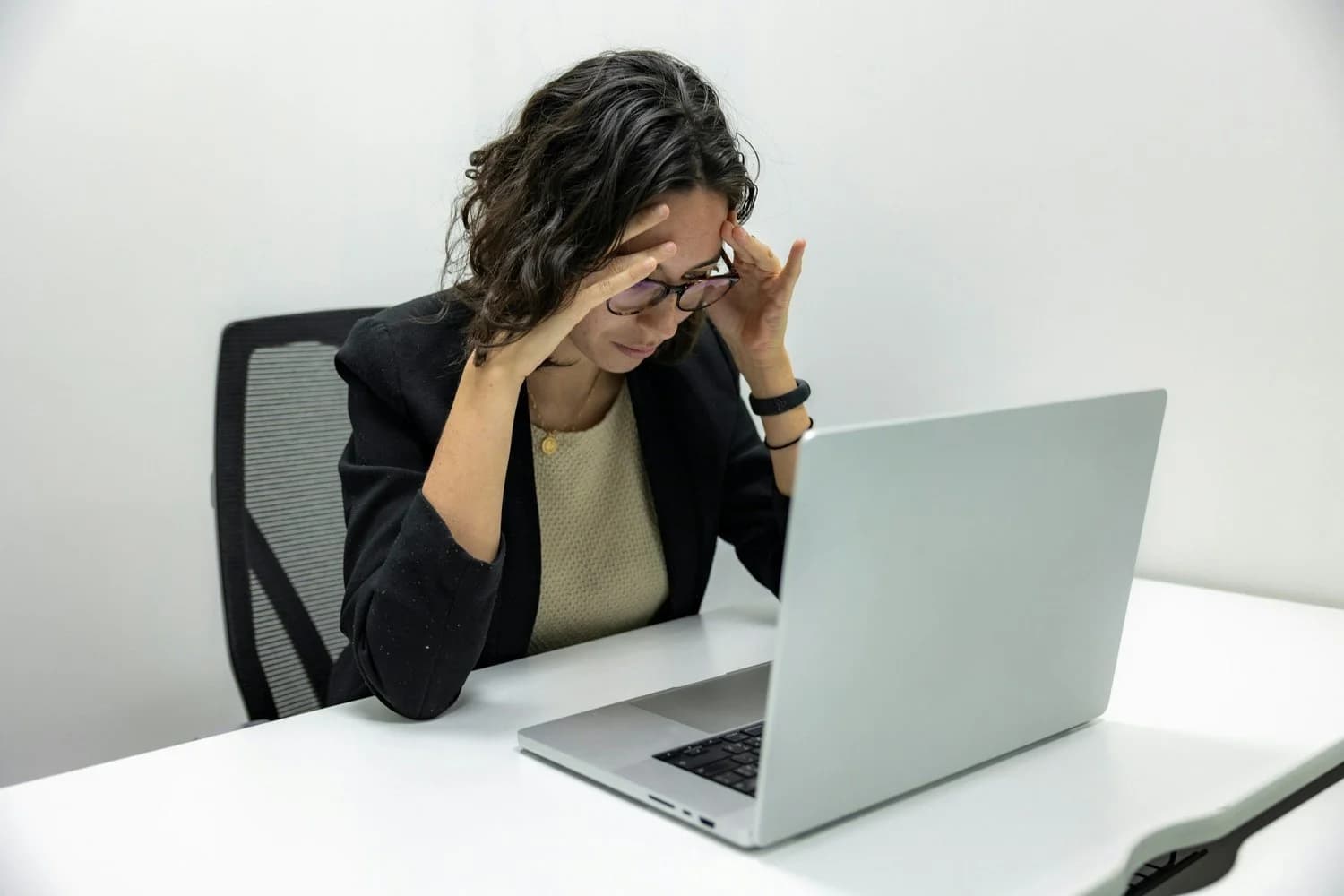 Frustrated woman with her head in her hand in front of a laptop