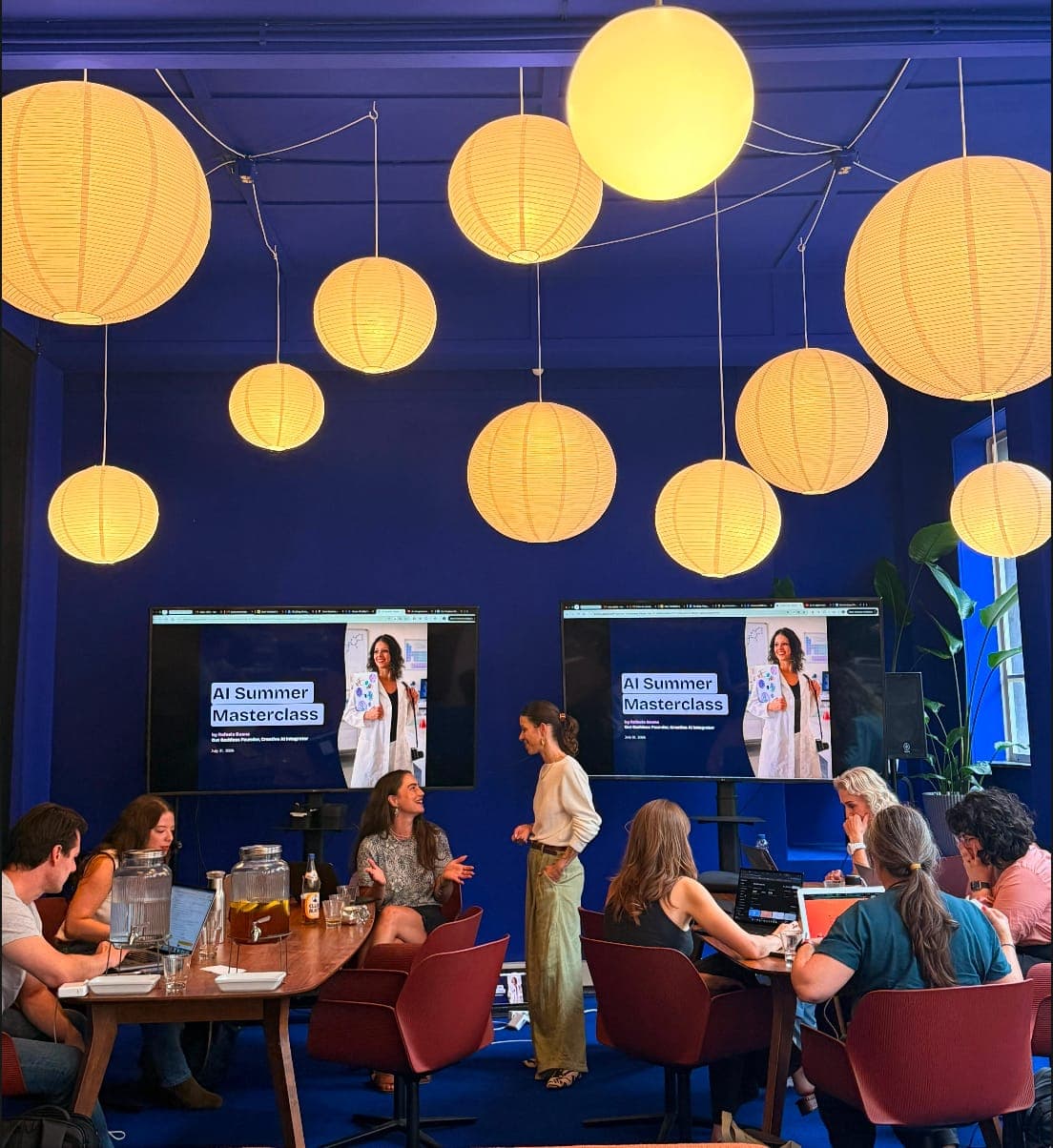 Participants at an AI workshop by Rafaela Buena in a room with paper lanterns