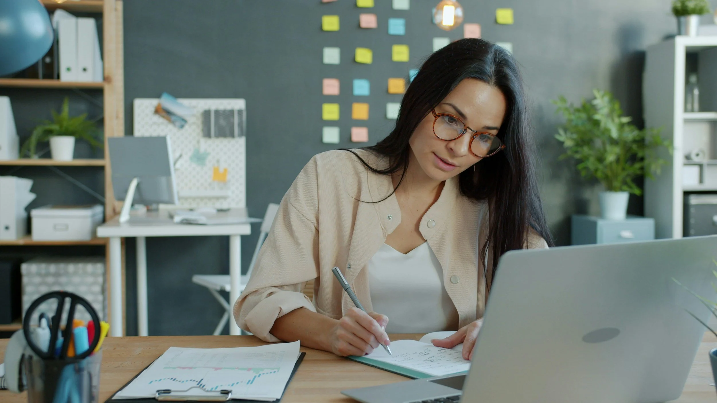 Woman taking notes next to her laptop