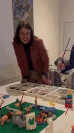 A participant laughing as she leans over her LEGO® model at a workshop table