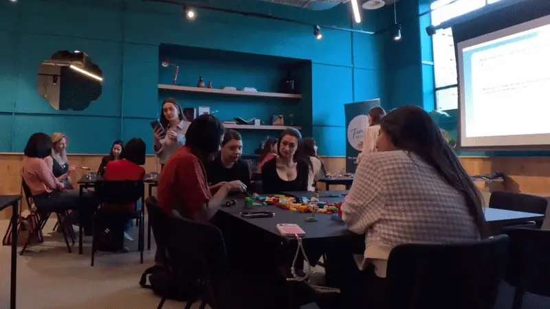 Teams building with LEGO® bricks at tables during a workshop by Rafaela Buena